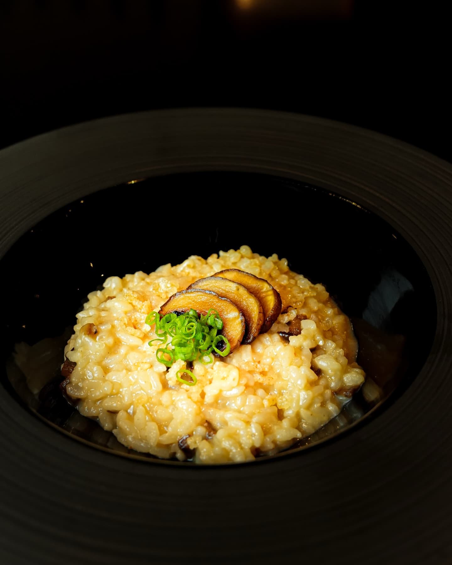 Crab and egg rice topped with sliced mushroom in a black bowl